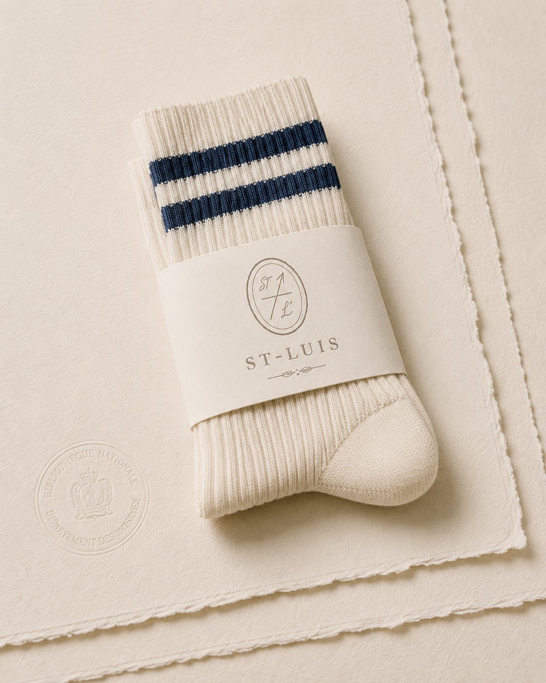 Cream tennis sock with navy stripes folded on cream paper with ST-LUIS band